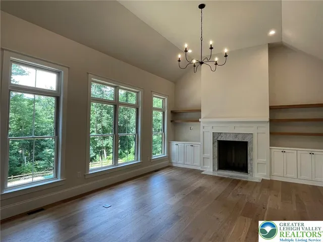 a living room with a fireplace chandelier and wooden floor