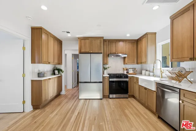 a kitchen with a sink wooden floor and stainless steel appliances