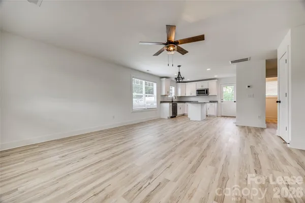 a view of a kitchen with a wooden floor and a ceiling fan