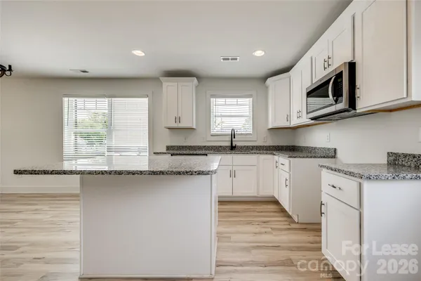 a kitchen with stainless steel appliances granite countertop a stove a sink and a microwave