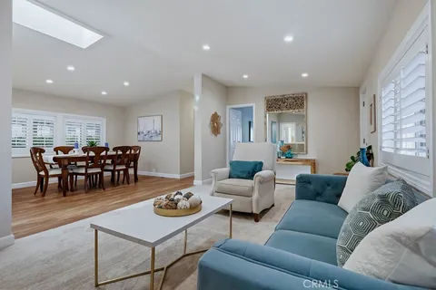 a kitchen with stainless steel appliances granite countertop a refrigerator a sink dishwasher a stove and white cabinets with wooden floor