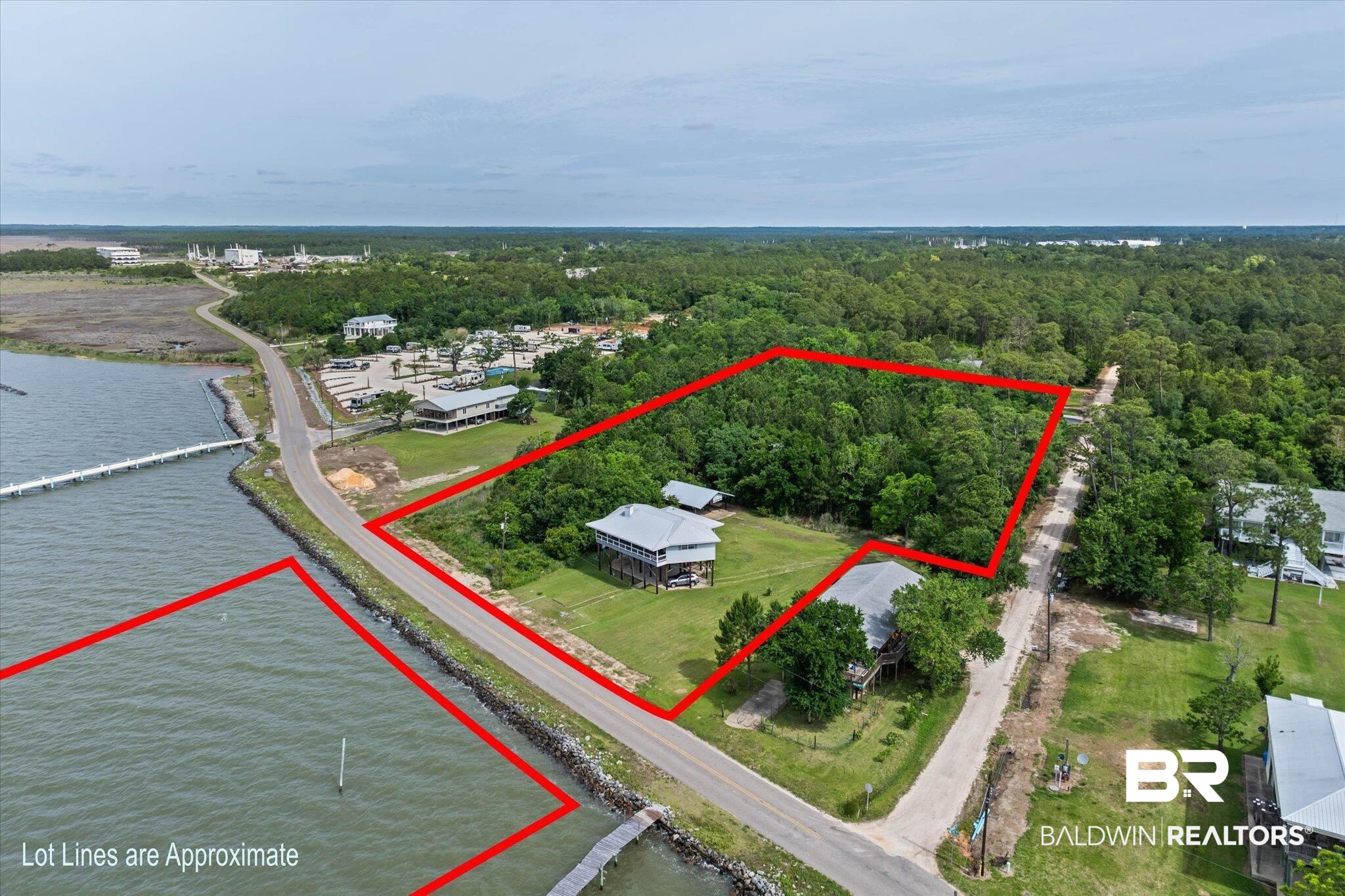 9100 Shell Belt Road Coden, AL 36523 - Photo 23 of 38 Expansive land parcel featuring dense tree coverage, bordered by a paved road and a waterfront