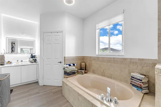 a bathroom with a tub a sink and a window