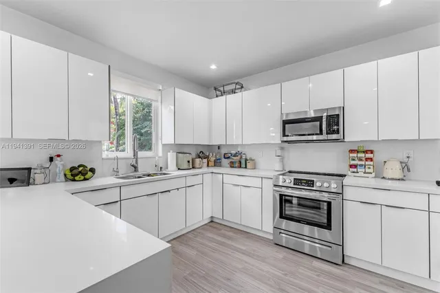 a kitchen with cabinets appliances a sink and a window