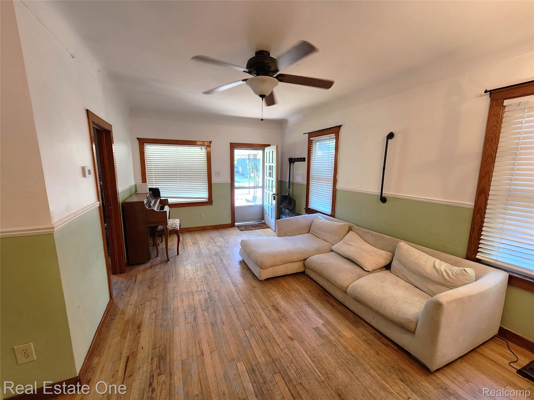 2153 Wiltshire Road Berkley, MI 48072 - Photo 2 of 18 Spacious living area featuring wood-finish flooring, a ceiling fan with integrated lighting, and multiple windows with blinds