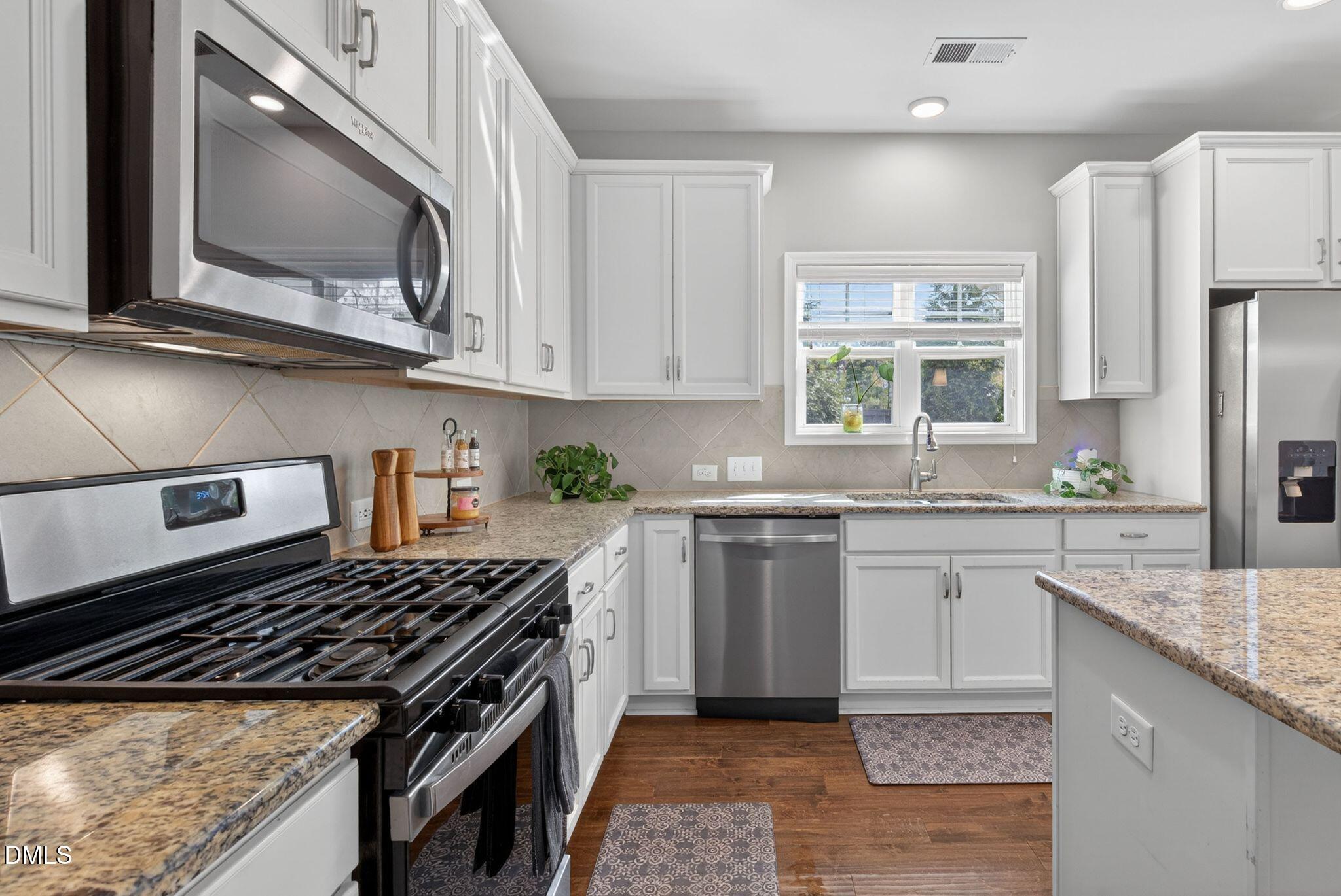 164 East Ravano Drive Clayton, NC 27527 - Photo 13 of 30 a kitchen with stainless steel appliances granite countertop a stove a sink and a microwave