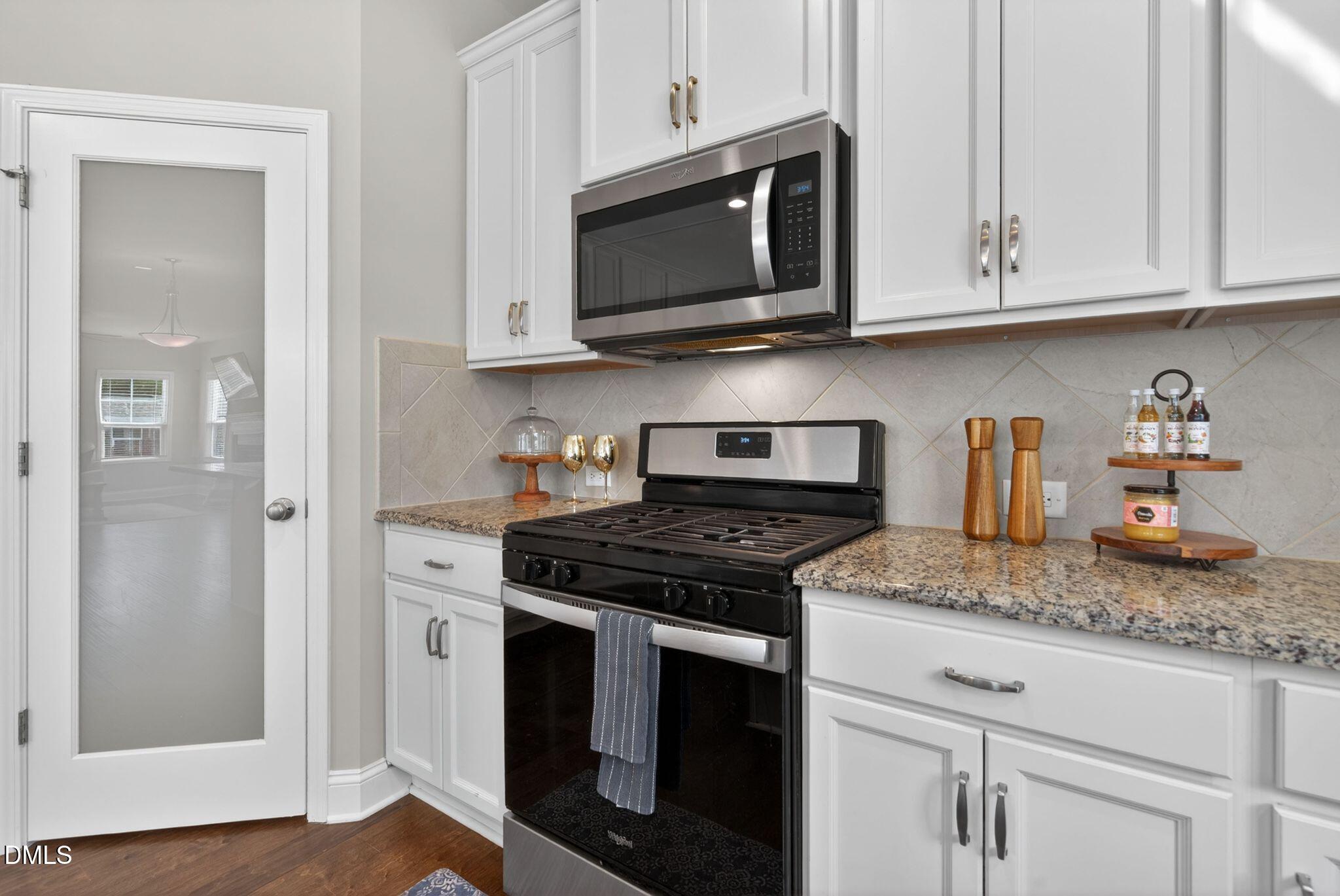 164 East Ravano Drive Clayton, NC 27527 - Photo 14 of 30 a kitchen with granite countertop stainless steel appliances white cabinets granite counter tops and a wooden floors