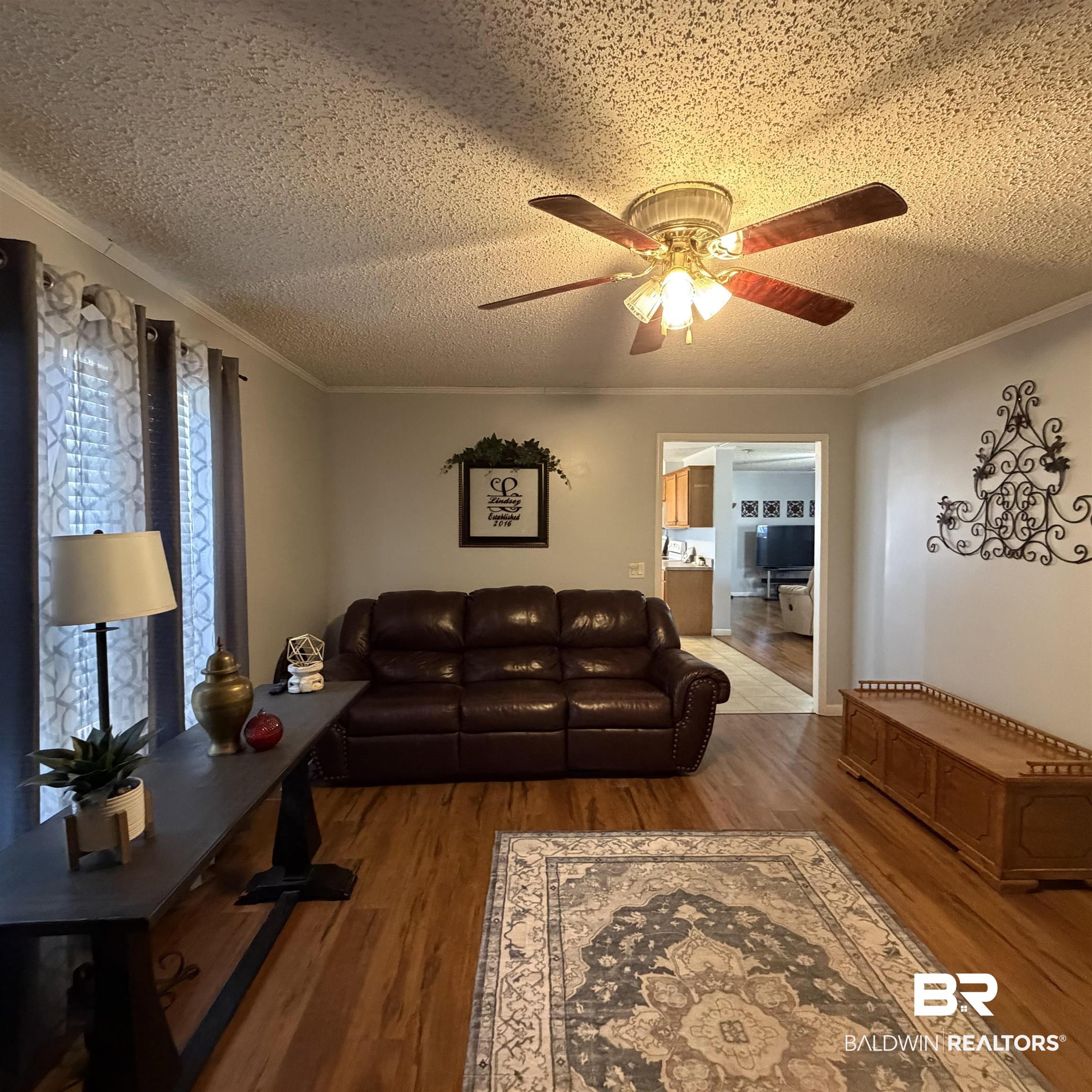 447 Sugar Hill Road Monroeville, AL 36460 - Photo 10 of 27 Living room with a textured ceiling, wood finished floors, ceiling fan, and ornamental molding