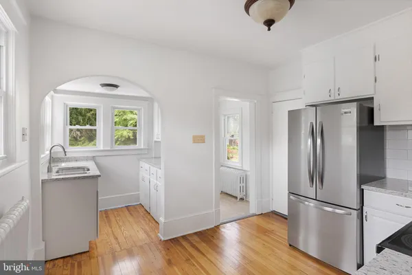 a kitchen with stainless steel appliances granite countertop a refrigerator a sink dishwasher a stove and a refrigerator with wooden floor