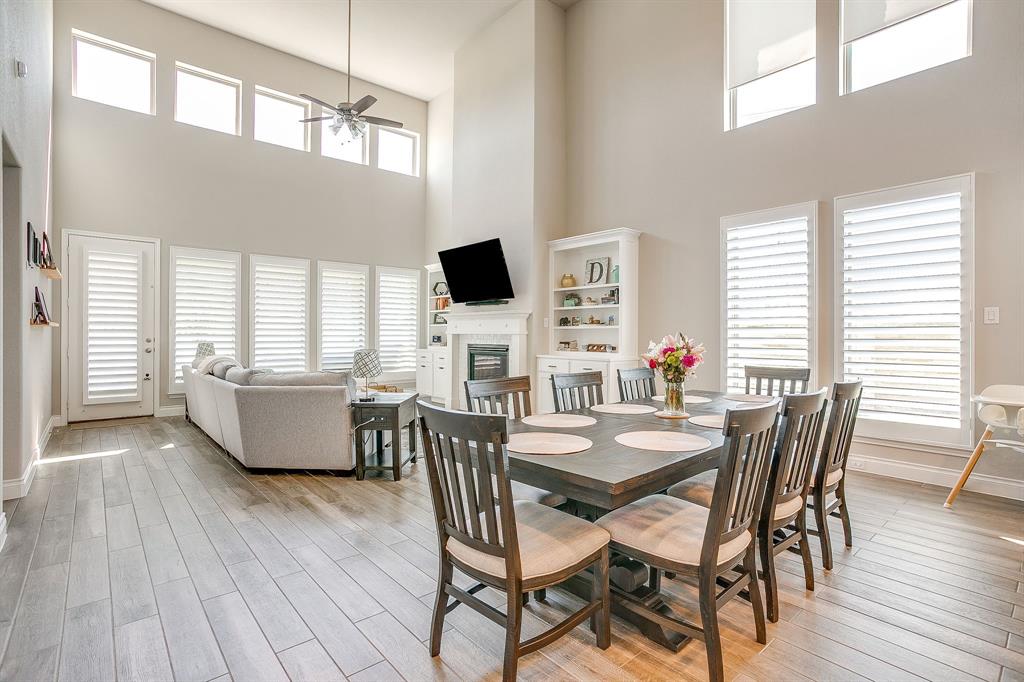 5709 Pope Creek Road Fort Worth, TX 76126 - Photo 11 of 39 Open-concept living and dining area featuring wood-look tile flooring, soaring ceilings, and walls of windows that fill the space with natural light.