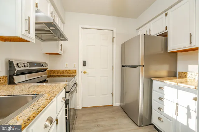 a kitchen with stainless steel appliances granite countertop a refrigerator and a stove