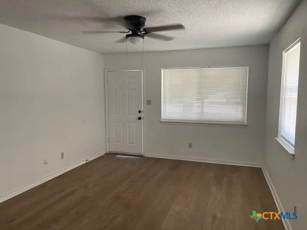 an empty room with wooden floor and windows