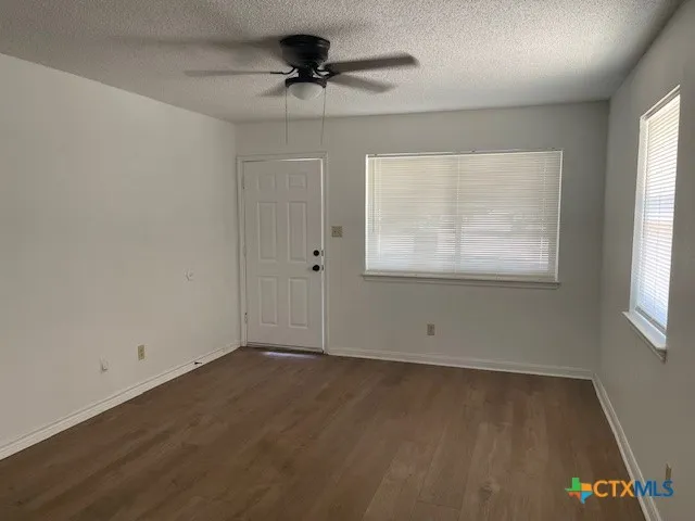 an empty room with wooden floor and windows