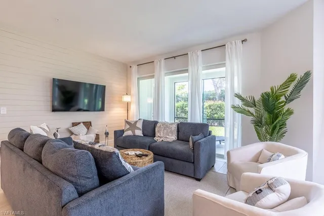 a living room with furniture a flat screen tv and a large window