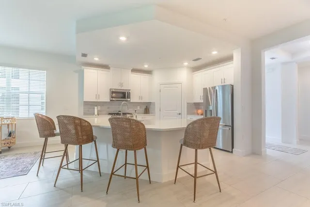 a kitchen with refrigerator a stove a dining table and chairs
