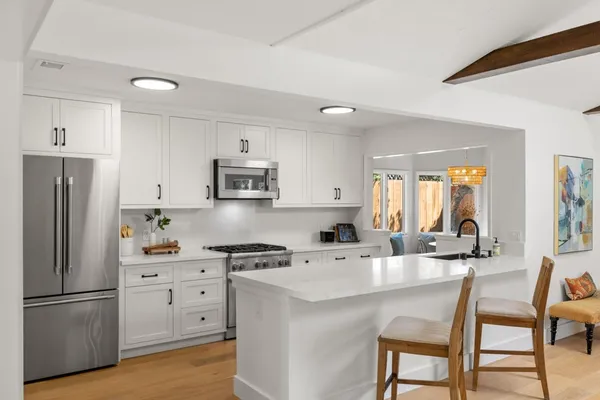 a kitchen with stainless steel appliances a refrigerator a stove a sink a dining table and chairs