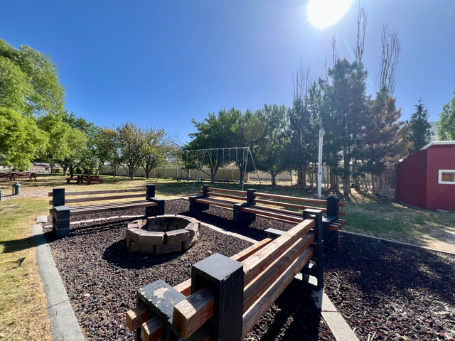 812 East Bates Cyn Road Tooele, UT 84074 - Photo 129 of 144 Outdoor fire pit surrounded by built-in wooden seating, featuring a gravel base and perimeter landscaping