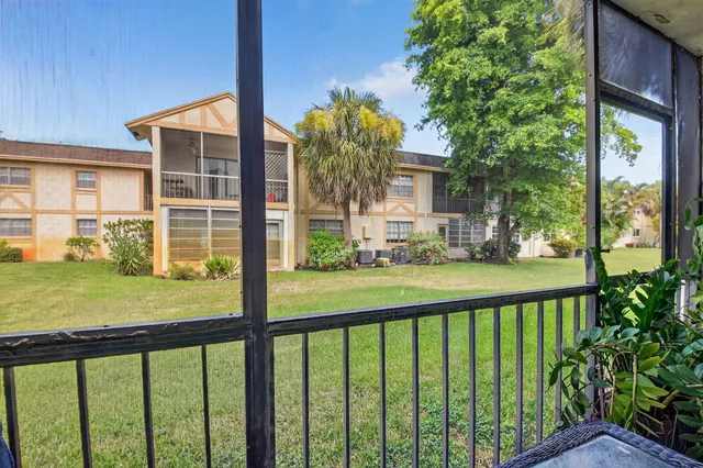 a view of a house with a large windows and flower plants