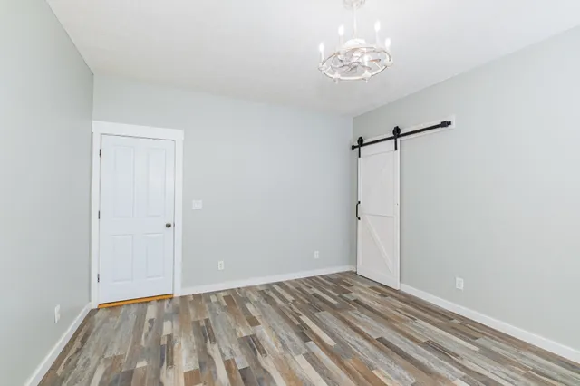 an empty room with chandelier fan and windows