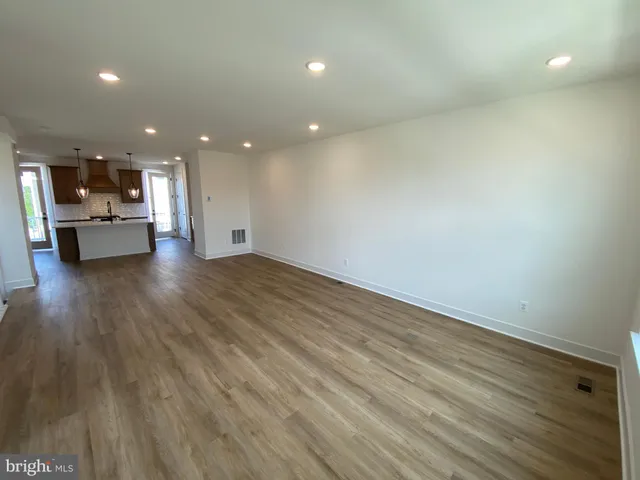 a large kitchen with kitchen island a stove a sink a center island and wooden floor