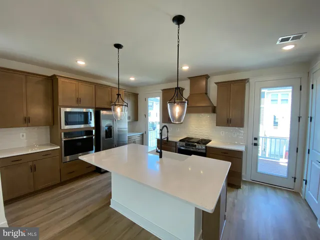 a large kitchen with stainless steel appliances a sink a refrigerator and a stove