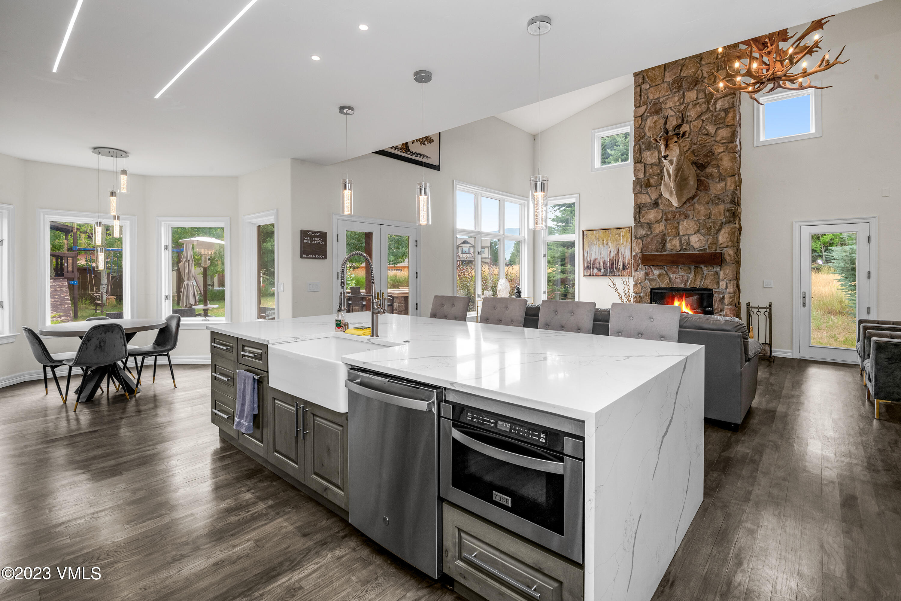 305 Red Fox Gypsum, CO 81637 - Photo 13 of 50 a large kitchen with stainless steel appliances a stove a sink dishwasher a dining table and chairs with wooden floor