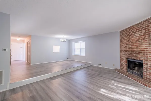 a view of empty room with wooden floor and fireplace