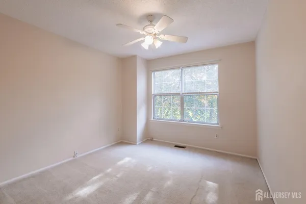 an empty room with windows and chandelier fan