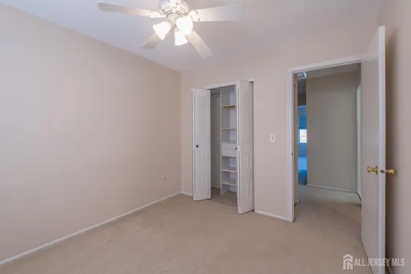 an empty room with closet and a chandelier fan