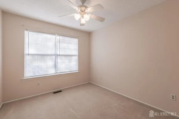an empty room with a window and a fan