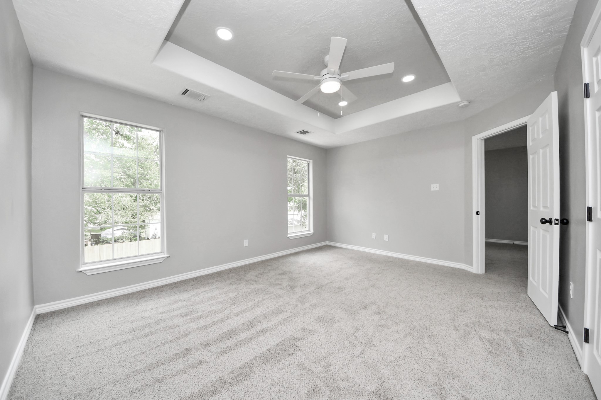 1105 East Kyle Road Clute, TX 77531 - Photo 23 of 44 The spacious primary bedroom has a tray ceiling, recessed lighting, and a ceiling fan. It has large windows providing natural light and is carpeted for comfort. It has a a bright and airy atmosphere.