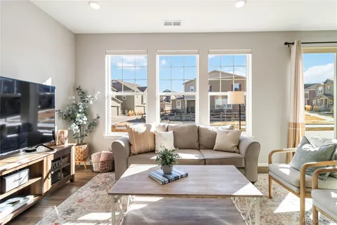 a living room with furniture a flat screen tv and large windows