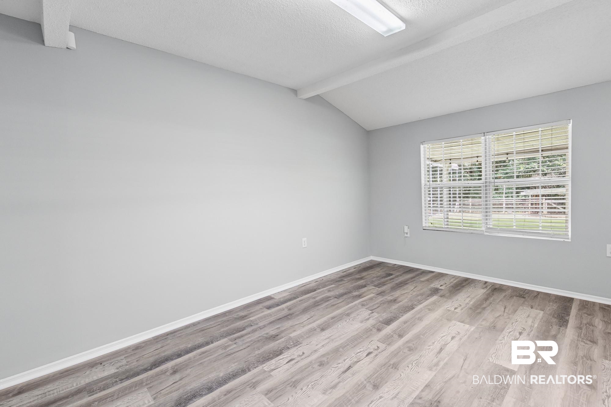 6933 Burbank Court Mobile, AL 36619 - Photo 13 of 25 Spacious room featuring vaulted ceilings with exposed beams, wood-finish flooring, and a large window with horizontal blinds