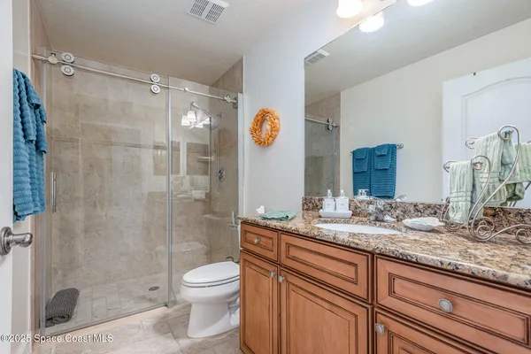 a bathroom with a granite countertop sink a toilet a mirror and shower