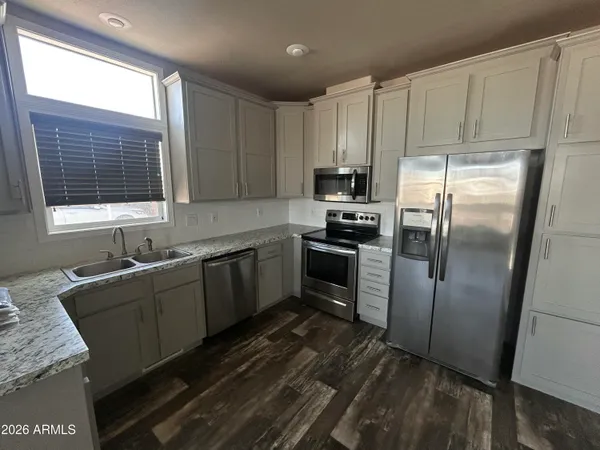 a kitchen with granite countertop a refrigerator and wooden cabinets