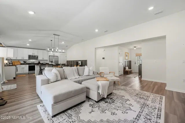 a living room with couches and kitchen view with wooden floor