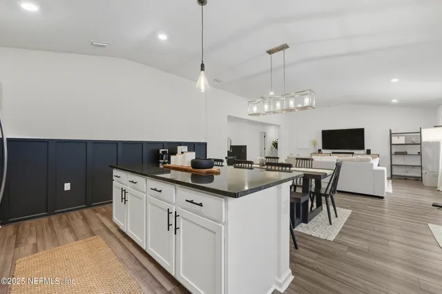 a kitchen with stainless steel appliances granite countertop a sink dishwasher a stove and a dining table with wooden floor