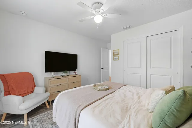 a bedroom with a bed a couch and a flat screen tv