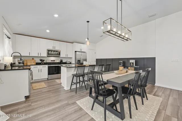 a view of a dining room with furniture a kitchen and chandelier