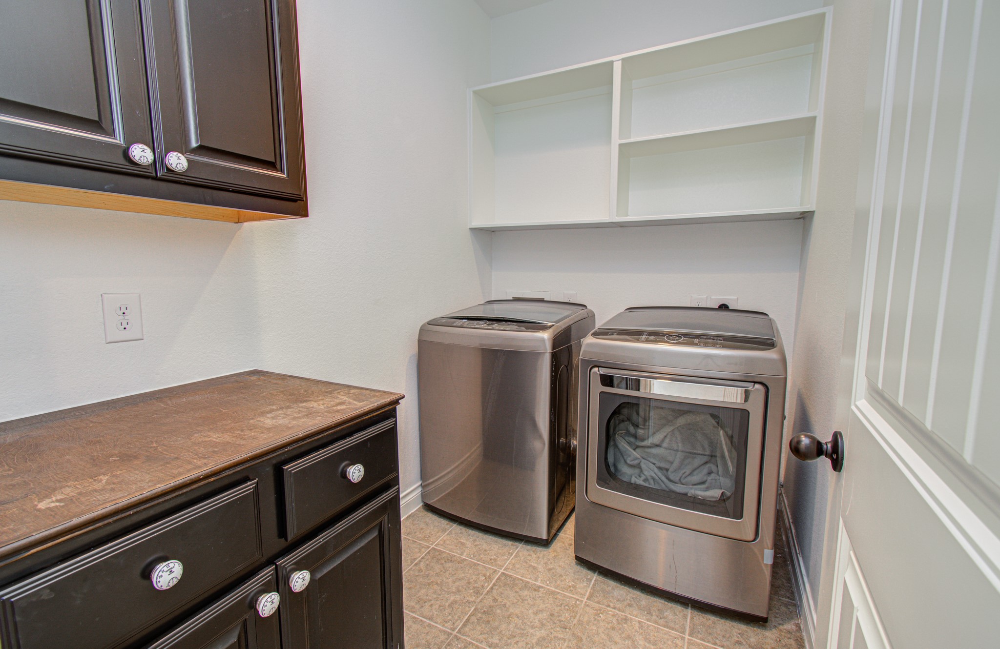6621 North Main Street Houston, TX 77009 - Photo 14 of 41 Located on the second floor this is a compact laundry room featuring modern appliances, dark cabinetry, and a countertop for folding, providing efficient storage and workspace.