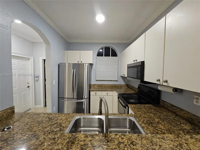 a kitchen with kitchen island granite countertop a refrigerator and a sink