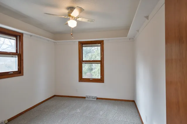 an empty room with windows and fan
