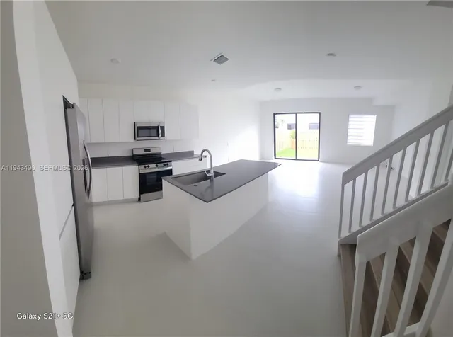 a living room with stainless steel appliances furniture a window and a view of kitchen
