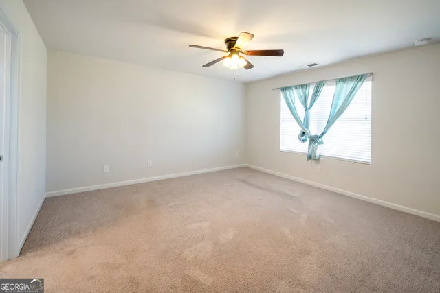 an empty room with windows and fan