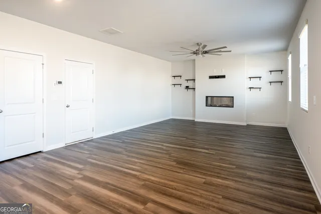 an empty room with wooden floor ceiling fan and windows
