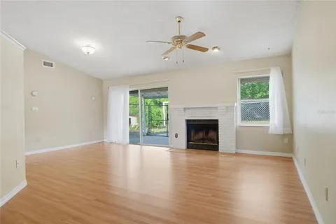 a view of an empty room with wooden floor fireplace and a window
