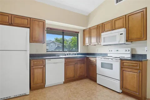 a kitchen with granite countertop white cabinets and white appliances