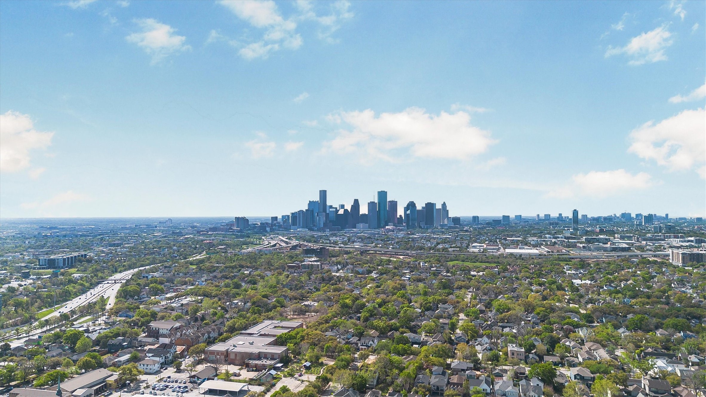 210 Tabor Street Houston, TX 77009 - Photo 18 of 18 Aerial view of a vibrant cityscape with a mix of urban and residential areas. The skyline features modern skyscrapers, and the area is lush with trees, offering a blend of city life and suburban charm. Perfect for those seeking proximity to downtown amenities.