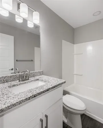 a bathroom with a granite countertop sink toilet and a mirror