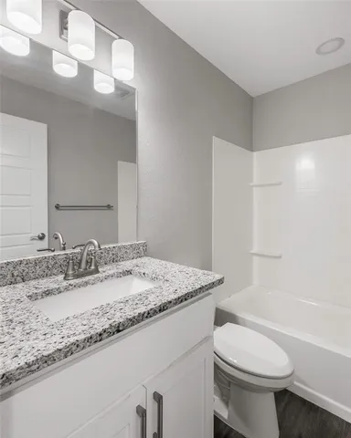 a bathroom with a granite countertop sink toilet and a mirror